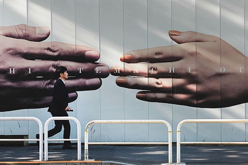 Person walking past a mural of hands shaking, representing the need to build trust to avoid branded podcast mistakes.