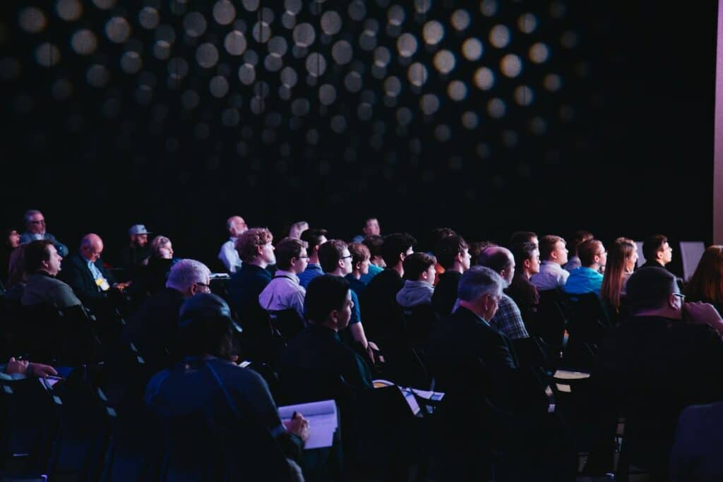Audience members seated and attentively listening to a presentation, illustrating the significance of avoiding branded podcast mistakes to keep listeners engaged.