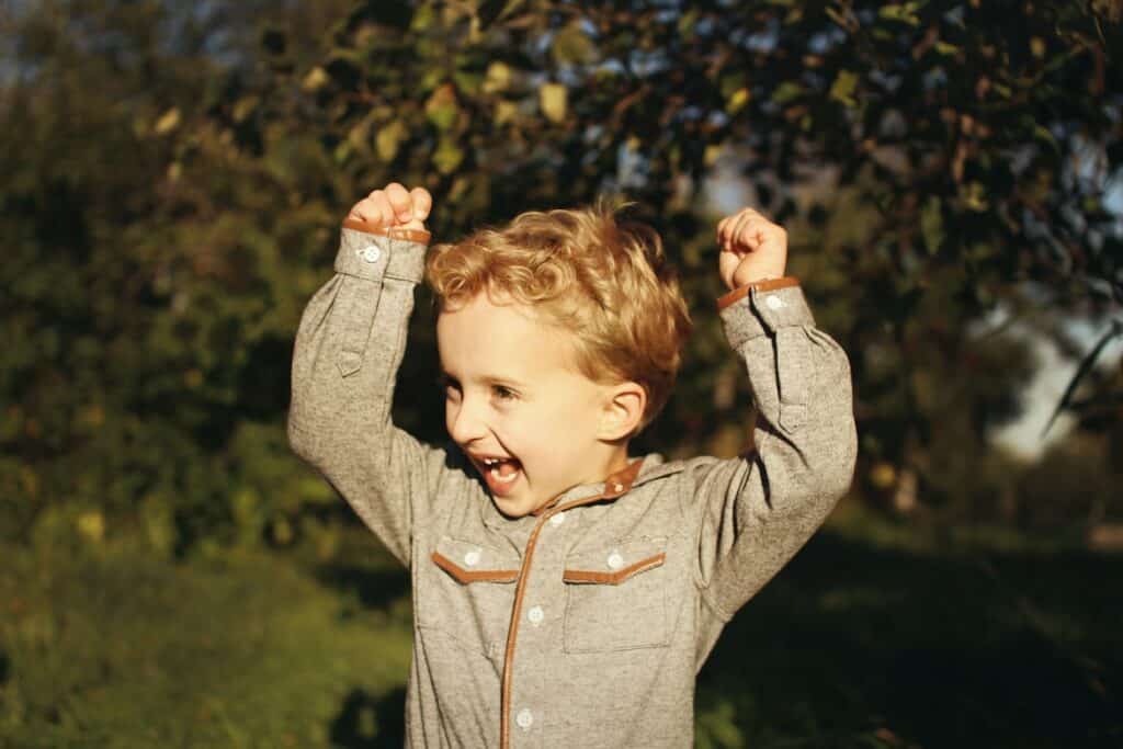 Child joyfully raising their arms, representing the positive impact of avoiding branded podcast mistakes for successful engagement.