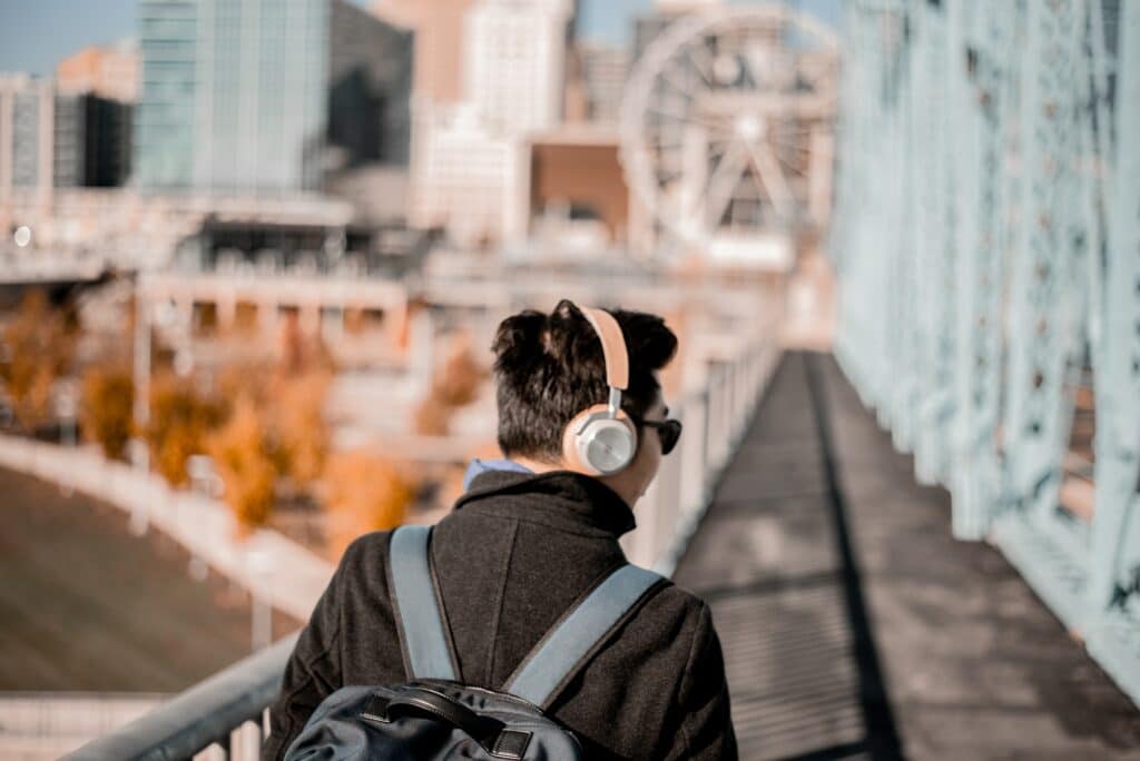 guy listening while walking on a bridge